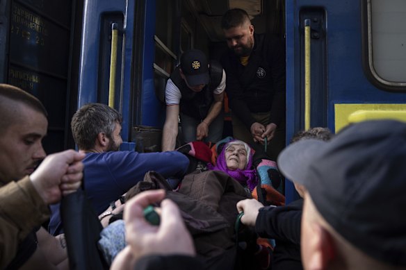 Rescue workers help a disabled elderly woman onto an evacuation train in Pokrovsk.