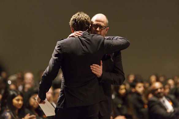 Artists Ben Quilty and Matthew Sleeth embrace before Sleeth's eulogy.