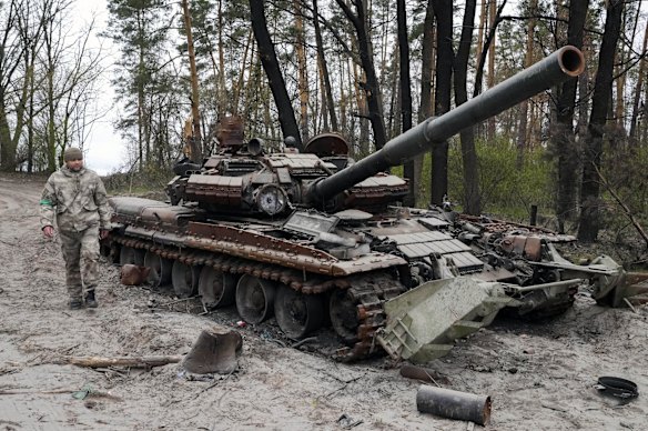 A Ukrainian soldier walks past an abandoned Russian tank after recent battles at the village of Moshchun, close to Kyiv.