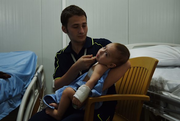 Hisham Haitham comforts his wounded baby cousin Qasid Radhwan at the Athba Field Hospital. Qasid was hit by shrapnel when his family fled Old Mosul and was confronted by a suicide bomber.