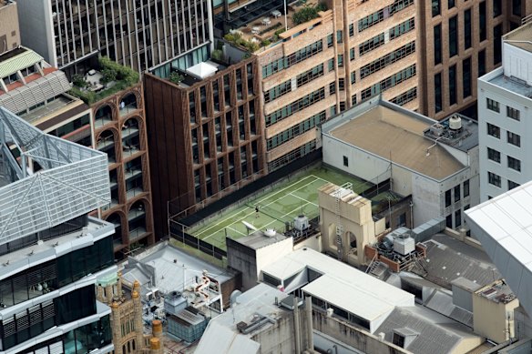 A lone woman does stretches on a rooftop tennis court, viewed from the Centrepoint Tower Observation Deck, in Sydney. 