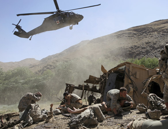 An Army soldier covers an injured comrade as a helicopter lands to evacuate the wounded after their armored vehicle hit an improvised explosive device in the Tangi Valley of Afghanistan’s Wardak Province in 2009.