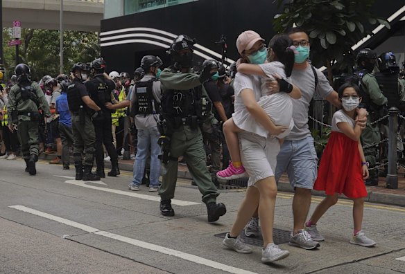 A family walks away as riot police fired tear gas during a protest against Beijing's national security legislation in Hong Kong.