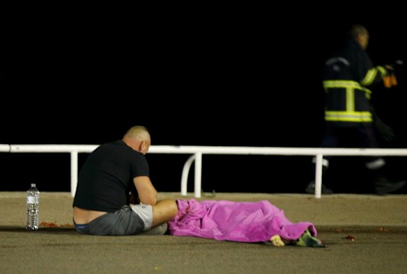  A man sits next to a body seen on the ground in Nice, France, when a truck ran into a crowd celebrating the Bastille Day national holiday July 14.  