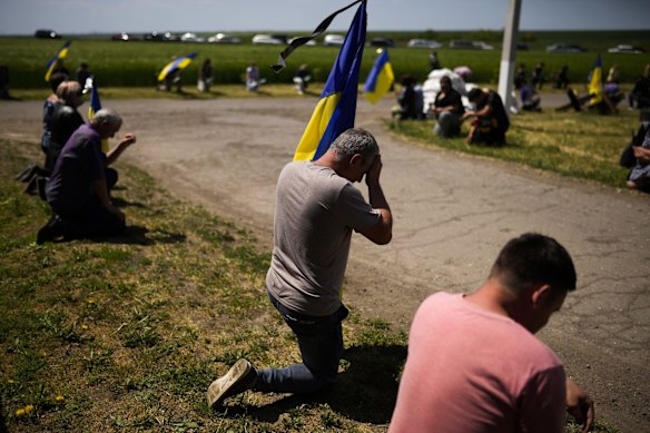 Mourners kneel as they await the coffin of Volodymyr Losev, 38, to pass during his funeral in Zorya Truda. Losev, a Ukrainian volunteer soldier, was killed on May 7 when the military vehicle he was driving ran over a mine in eastern Ukraine.
