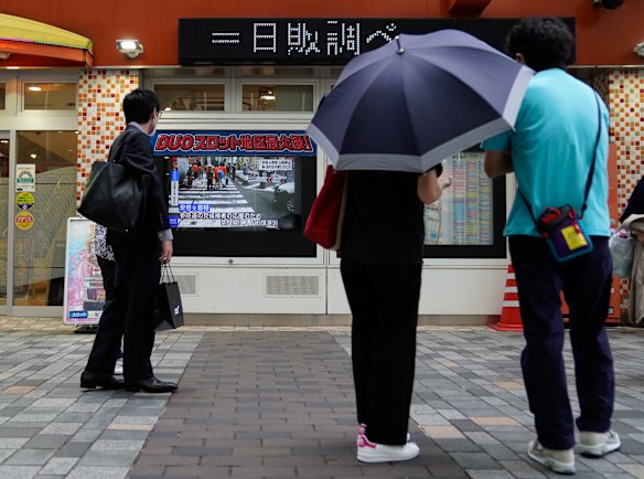 Passersby watch reports of the shooting, which took place in Nara, Japan.
