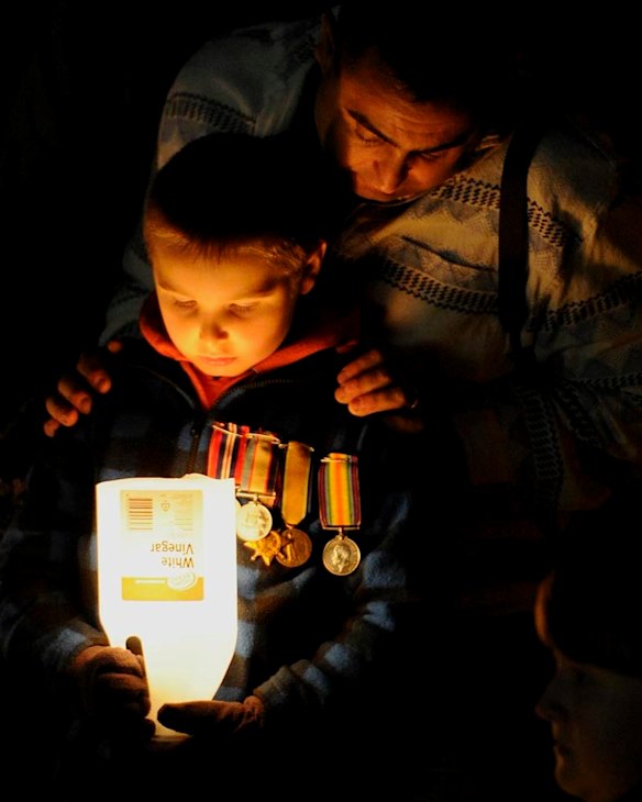 Adam Smith from Ngunnawal with son Joshua, 8 years old, during the ANZAC Day dawn service at the Australian War Memorial in Canberra.