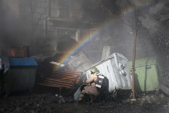 An anti-government protester finds cover during clashes with riot police outside Ukraine's parliament in Kiev, Ukraine, Tuesday, Feb. 18, 2014. Thousands of angry anti-government protesters clashed with police in a new eruption of violence following new maneuvering by Russia and the European Union to gain influence over this former Soviet republic.
