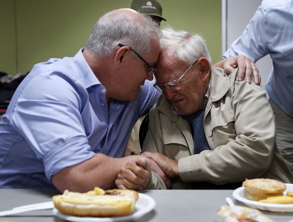 Prime Minister Scott Morrison comforts 85 year old Owen Whalan of Half Chain road in Koorainghat who has been evacuated from his home, during a visit to Club Taree Evacuation Centre in Taree, New South Wales.