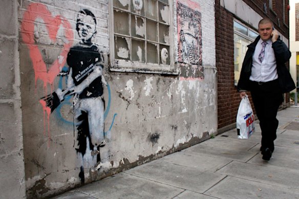 A man walks past artwork by renowned street artist Banksy in East London.