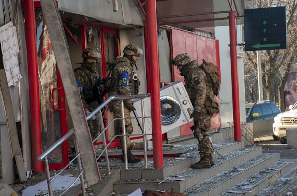 Ukrainian servicemen carry a washing machine as they help to relocate goods from a market that was destroyed by shelling in Kharkiv.
