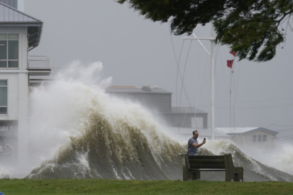 A man takes pictures of high waves along the shore of Lake Pontchartrain as Hurricane Ida approaches.