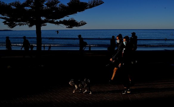 People wearing masks exercise at Manly Beach on sunday. 