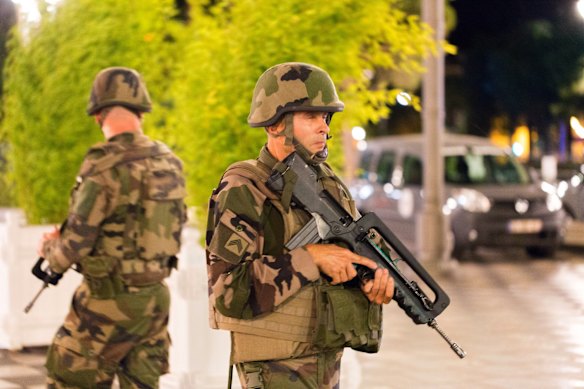 French soldiers stand guard by the sealed off area of an attack after a truck drove on to the sidewalk and ploughed through a crowd of revelers.