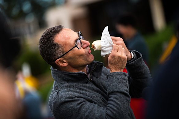 Federal Greens nominee Richard Di Natale enjoys at sausage sandwich at Nth Reservoir polling station in Melbourne.