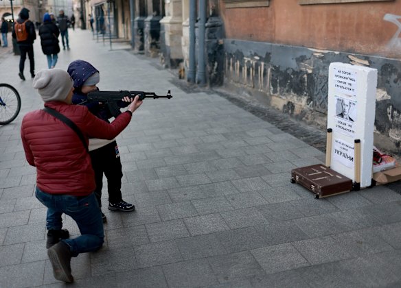 A child uses an air rifle to shoot at a target with the face of Russian President Vladimir Putin on it in Lviv.