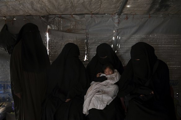 Sahra Ahmed (left), Kawsar Abbas (2nd from left), Aisha Ahmed (2nd from right) Zeinab Ahmad (right) look down at one of the Australian babies, Layla, in Al-Hawl camp in North East Syria.