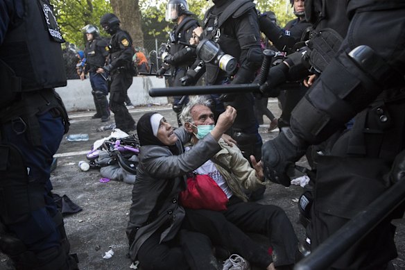 A woman pleads with police after her husband was cut on the head as migrants clashed with police on the Hungarian border with Serbia.