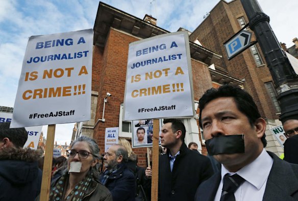 Journalists hold up placards as they demonstrate across the street from Egypt's embassy in central London, Wednesday, Feb. 19, 2014.