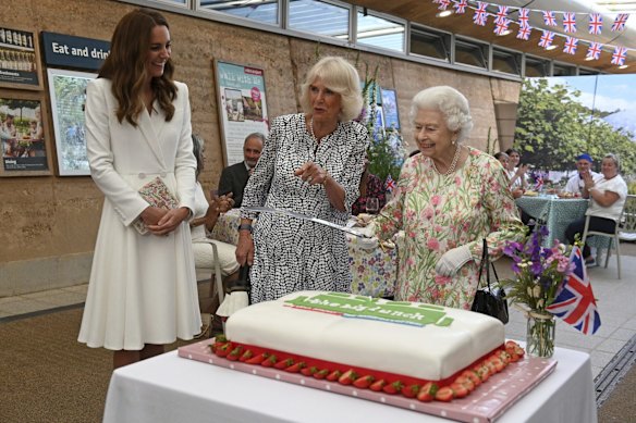Britain's Queen Elizabeth II, centre right,  Camilla, the Duchess of Cornwall, centre and Kate, the Duchess of Cambridge react as the Queen prepares to cut a cake as they attend an event in celebration of 'The Big Lunch 'initiative, during the G7 summit in Cornwall, England, Friday June 11, 2021.