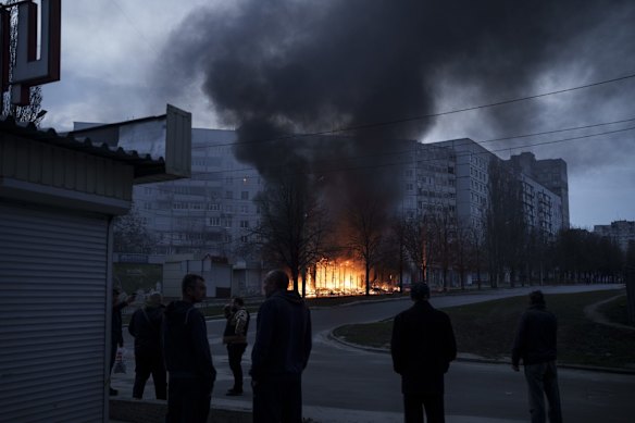 Residents stand outside their apartments as shops burn after a Russian attack in Kharkiv.