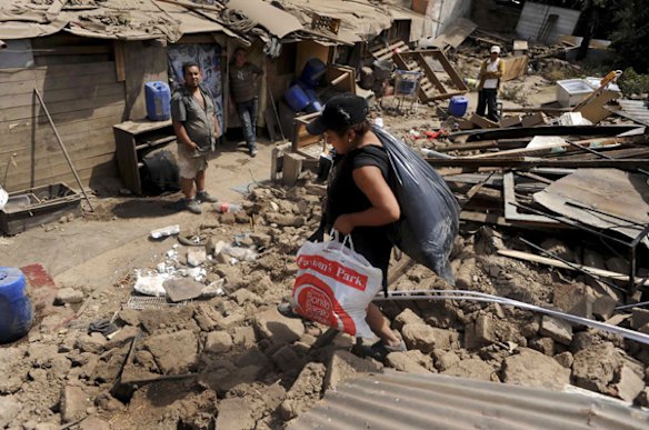 An immigrant from Peru recovers her belongings after a major earthquake destroyed homes along Santo Domingo Street in Santiago.