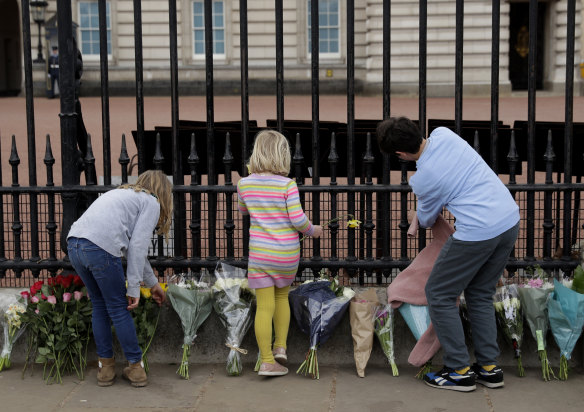 Young children leave flowers in front of the gate at Buckingham Palace in London, after the announcement of the death of Britain’s Prince Philip.