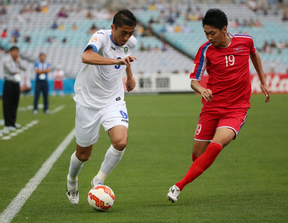 Captain fantastic: Uzbekistan skipper Odil Ahmedov holds off North Korea's Ri Yong Jik.
