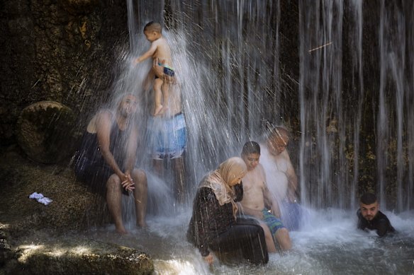 Israeli Arabs stand under a waterfall during the Muslim Eid al-Adha holiday at the Gan HaShlosha national park near the northern Israeli town of Beit Shean.