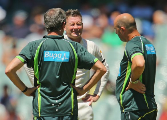 Michael Clarke of Australia reacts as he injures his back as he is tended to by Peter Brukner, left, Australian Team Doctor and Alex Kountouris, Australian Team Physiotherapist.
