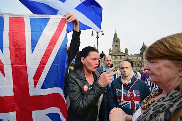A Yes supporter talks with a man and a woman with a Union flag in George Square.