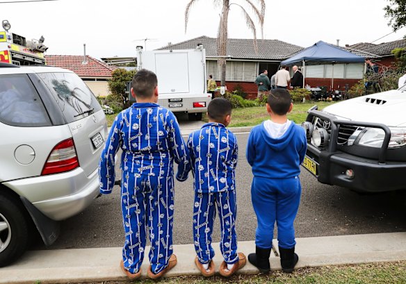Neighbourhood kids watch police remove kilos of drugs after raiding a house in Georges Hall, Sydney.