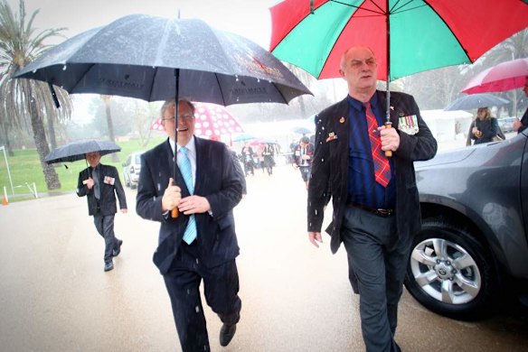 Prime Minister Kevin Rudd seeks cover from the rain with Long Tan veteran Alan Fraser R at a gunfire breakfast in Adelaide.