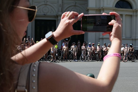 A member of the public takes a photo of the cyclists participating in the 2021 Naked Bike Ride at Royal Exhibition Building.