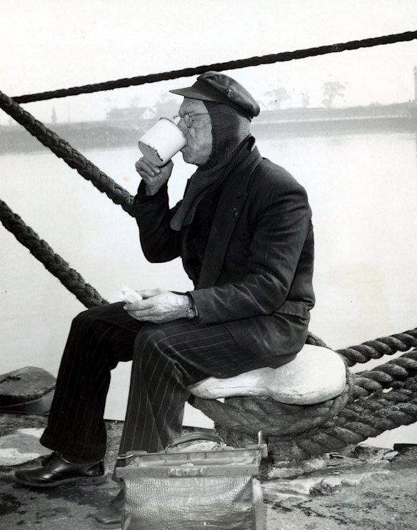 Veteran wharfie Mick O'Brien on his morning tea break by the Yarra River at South Wharf, 1963. Photo: Jack Faithfull