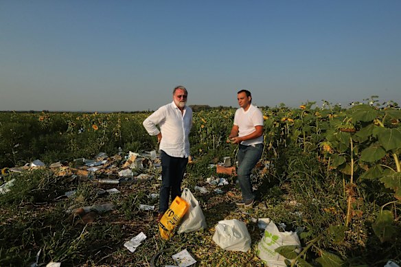 Sydney Morning Herald chief correspondent Paul McGeough (left) with bags of collected sunflowers picked for the families and friends of victims who died in the shooting down of flight MH17 at the crash site on the outskirts of the village of Rassyypnoye.