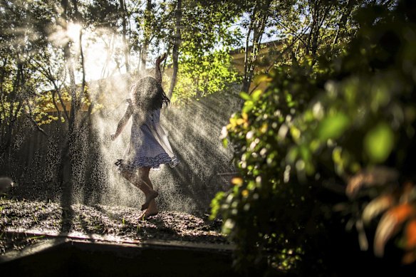 Five-year-old Eliza Ellinghausen plays in the backyard as the lawn gets watered. 