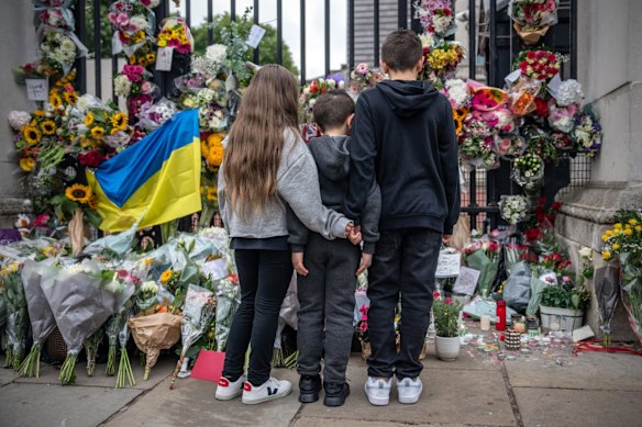 Children pause next to flowers and tributes to Queen Elizabeth II outside Buckingham Palace on September 9, 2022.