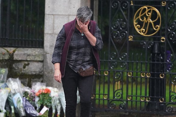 A woman appears emotional after laying flowers at the gates of Balmoral in Scotland following the death of Queen Elizabeth II.
