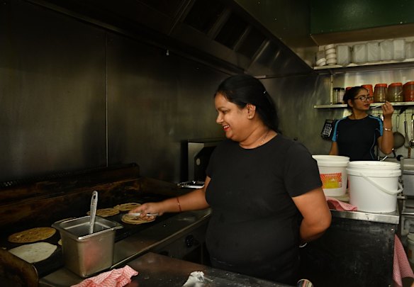 Women cook food at a busy restaurant in Harris Park. 