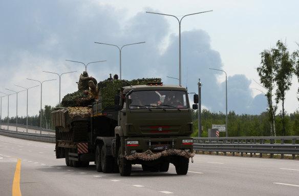 Fighters of Wagner private mercenary group transport a tank along M-4 highway, which links the capital Moscow with Russia’s southern cities, with smoke from a burning oil depot seen in the background, near Voronezh, on Saturday. 