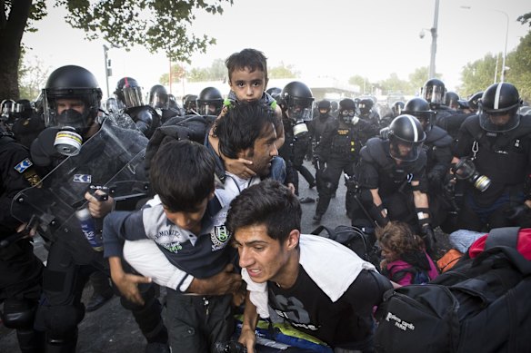 A family flees after Hungarian police responded with force against migrants protesting on the Serbia-Hungary border.