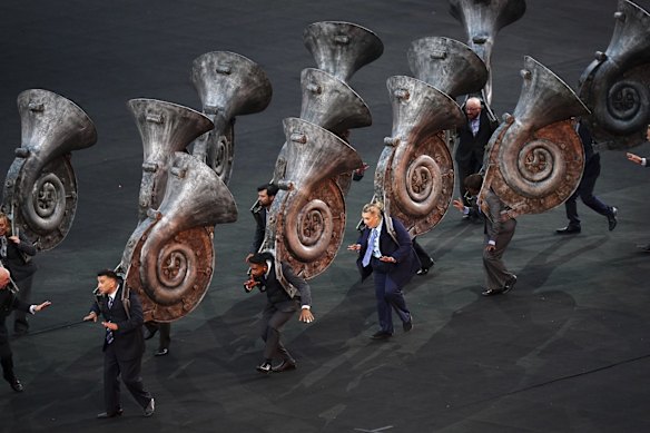 Performers carry large musical instruments.