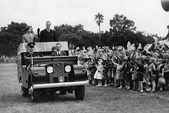 Queen Elizabeth and the Duke of Edinburgh drive through crowds of children at Hamilton Oval, Victoria.