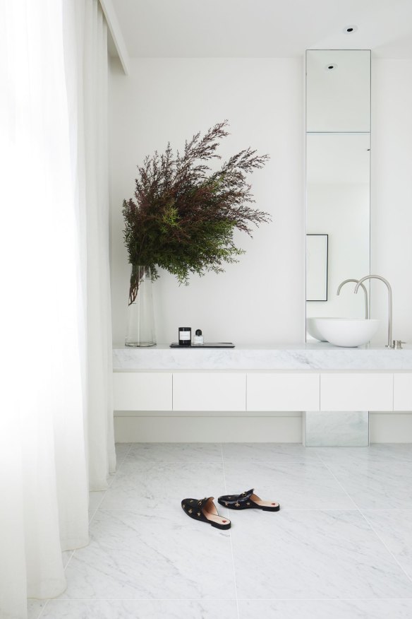 The opulent master bathroom features a marble vanity and floor. Sheer floor-to-ceiling linen curtains provide privacy while creating a lovely diffuse light.