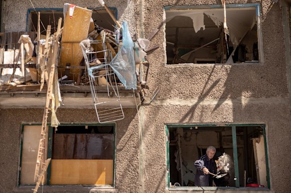 A man throws debris from the window of a residential apartment block damaged by a Russian missile strike, in Kramatorsk.