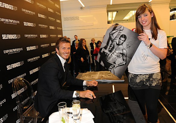 David Beckham gives a fan a thrill by signing a poster and a t-shirt at the unveiling of his new underwear campaign for Emporio Armani in London.