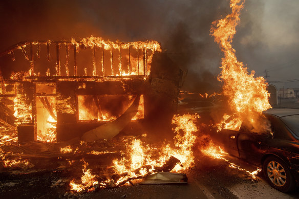 Flames consume a car and building as the Camp Fire tears through Paradise.