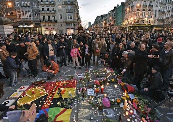 People bring flowers and candles to mourn at  the Place de la Bourse in the centre of Brussels.