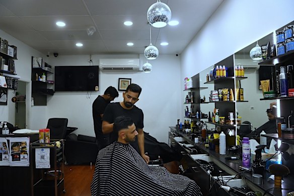 Subodh, 27, cuts Prince Singh's hair at a barber shop.